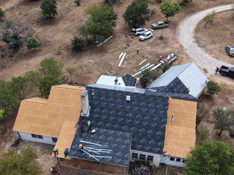 Job in progress: drone view of a crew installing a metal roof over new decking and underlayment